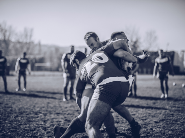 A group of rugby players tackling one another in a competitive match.