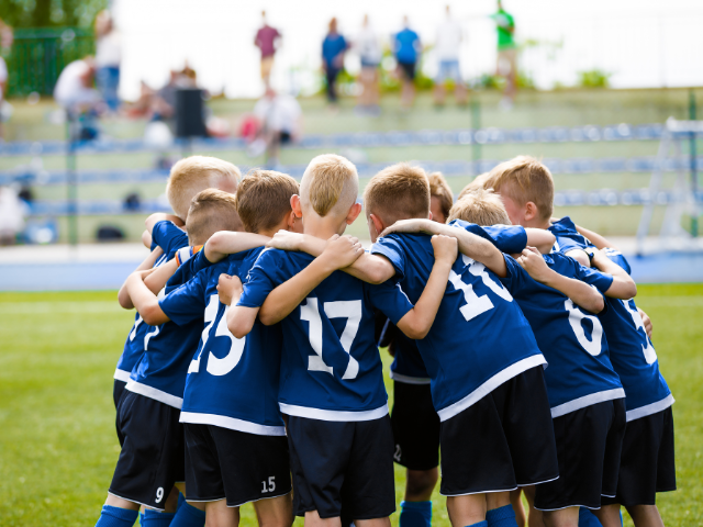 Rugby team in blue jerseys huddled on the field preparing for the game.